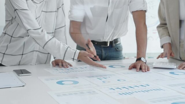 Professional team reviewing financial charts, working together in contemporary workspace, brainstorming strategic improvements, close up. Business people concept