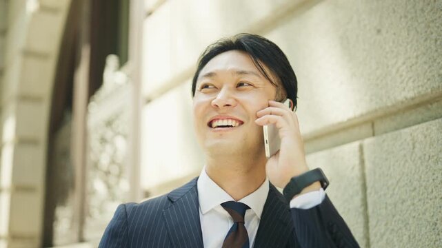 Japanese businessman on a phone call in front of a classic stone building