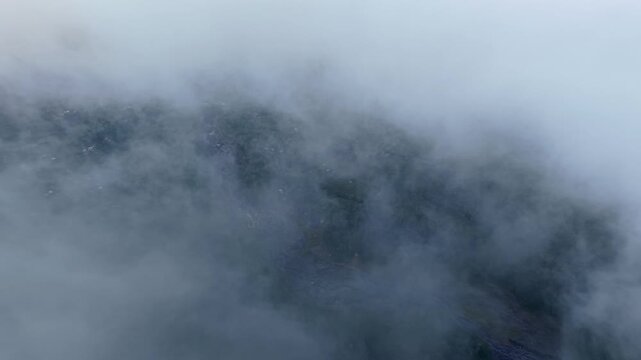 Thick fog wraps mountains, obscuring peaks and valleys. Silent. Draped in gray at Pronojiwo, Lumajang