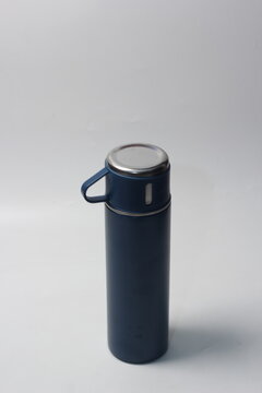 a sleek navy blue stainless steel thermos bottle standing upright with its matching cap handle on a plain neutral background.