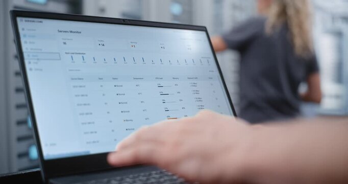 Male Network Engineer Monitors Server Telemetry as Critical Overheating Warning Appears, Analyzing System Metrics and Network Traffic While Responding to Infrastructure Performance Incident.