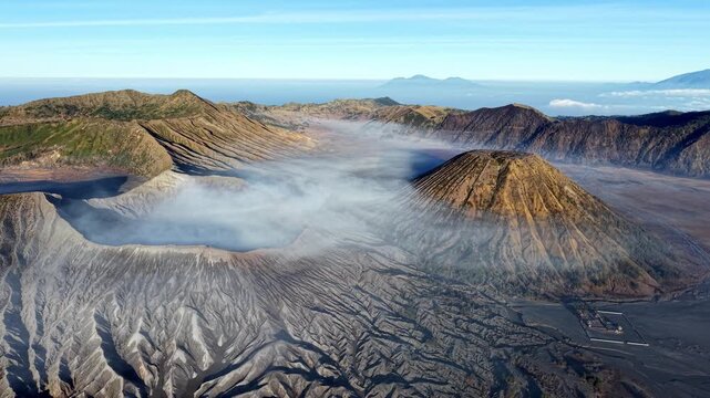 Dramatic daytime view of volcanic caldera with drifting smoke and textured ash plains