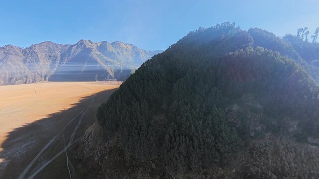 Fisheye aerial drone panorama of Bromo caldera hill with pine forest, golden plain, morning mist