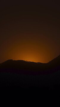 Vertical video - Timelapse of the sun rising behind the mountain silhouette
