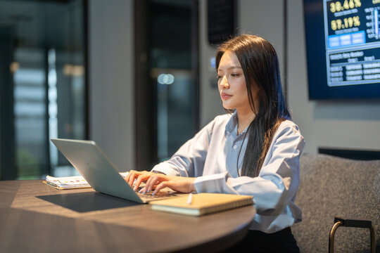 Smiling Asian business woman using laptop in modern digital workplace, Female corporate worker analyzing data technology in office, Financial management, software dashboards and tech startup concepts