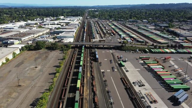 4K aerial drone footage of freight trains and rail yard in Portland, Oregon, USA, with railroad tracks, public transit bus facility, Holgate bridge and industrial transportation infrastructure