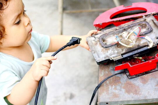 Curious toddler reaching broken appliance.