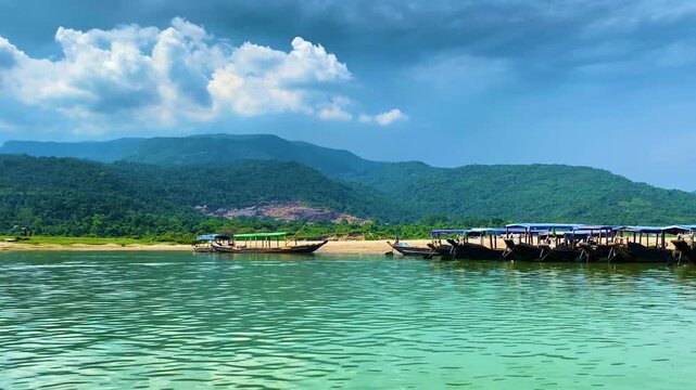 Tourist boats travel through scenic clear river at Sada Pathor in Sylhet, Bangladesh, with the Khasi Hills along the nearby Bangladesh-India border visible in the background