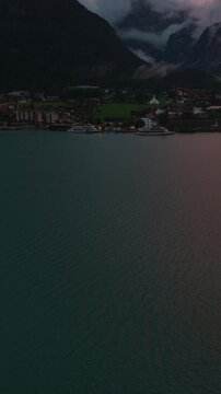 Vertical Aerial View of Achensee Lake Austria at Sunset with Alpine Village Mountains and Clouds