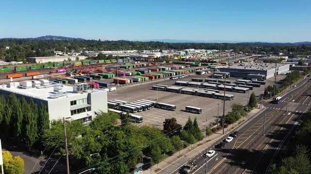 4K aerial drone footage of freight trains and rail yard in Portland, Oregon, USA, with railroad tracks, public transit bus facility, Holgate bridge and industrial transportation infrastructure