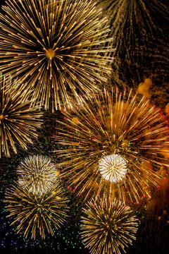 Overlapping golden fireworks filling a vertical frame