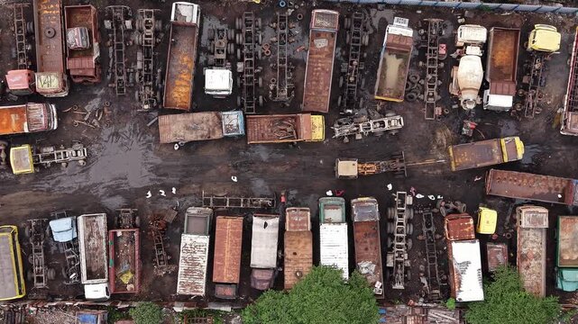 Rusty dismantled trucks arranged at vehicle scrapyard aerial auto salvage industry