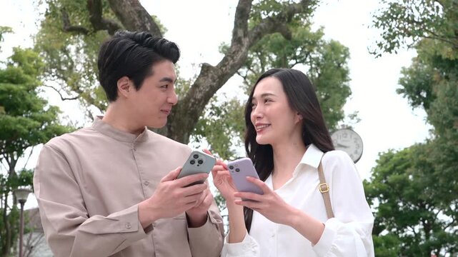 公園でスマホを使いながら話すカップル