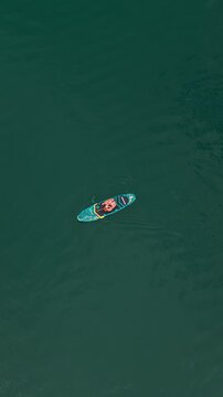 Top Down Orbit Drone View of Woman Paddle Boarding in Turquoise Achensee Lake Austria