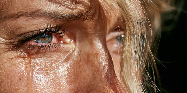 A close-up shot of a woman's eyes, with tears streaming down her face, conveying deep sadness and despair