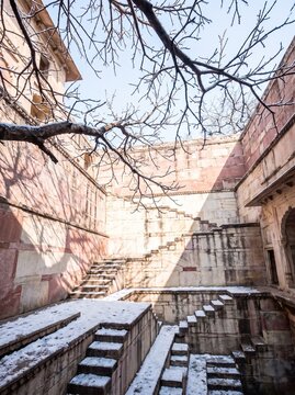 Ancient Indian Stepwell Architecture in Winter with Snow Covered Stone Stairs and Bare Tree Branches, Historical Heritage Site in Rajasthan, Traditional Water Harvesting Structure, Travel Photography