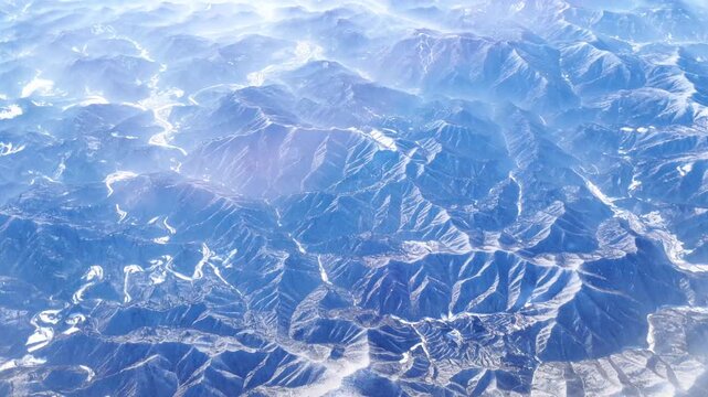 The tops of the mountains covered with snow view from the window of the plane.