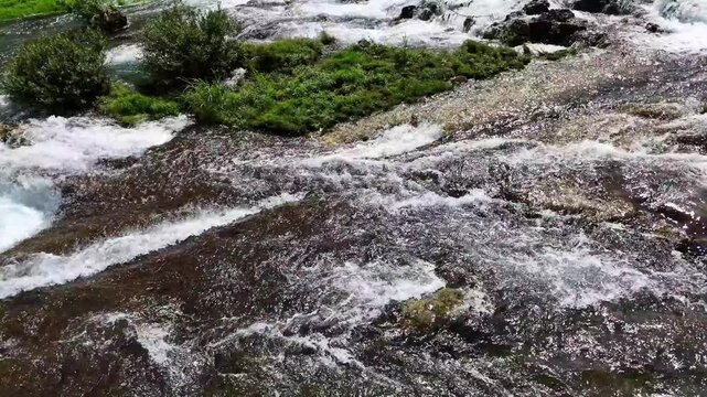 Cinematic aerial: High quality footage of clear river water flowing over stones for background use