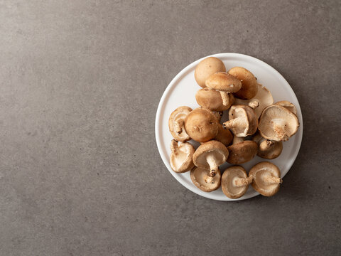 Fresh raw shiitake mushrooms piled on a white round plate