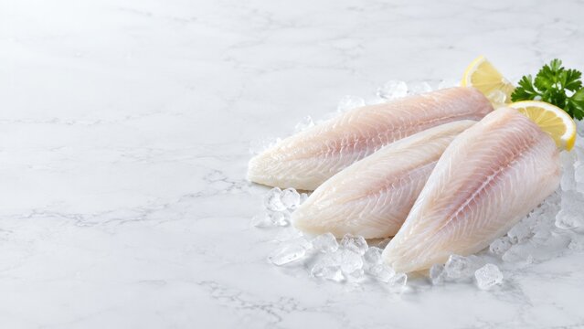 Raw white fish fillets with lemon and parsley on ice, healthy seafood concept for food advertising with copy space