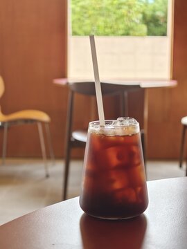 Iced Coffee Glass on Wooden Table in Cozy Cafe
