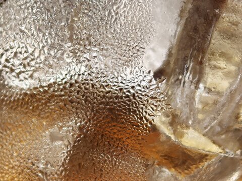 Macro Ice Cube With Golden Drink Reflections