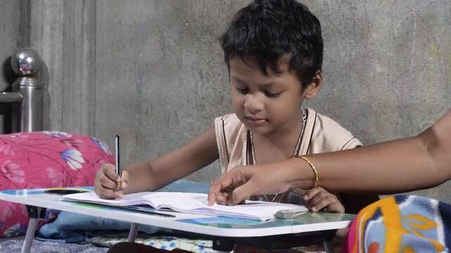 Young child writing in a notebook with guidance at a study table