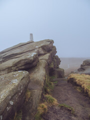 A foggy view of the trig point of Back Tor, with a path in the background on top of Derwent Moor, Peak District © Dave Harrison-Ward