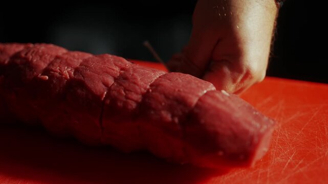 Raw beef roast seasoned with pepper on a red cutting board