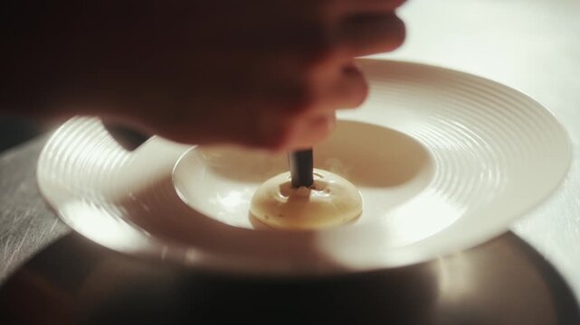 Close-up of a hand sprinkling seasoning onto a dish in a hotel kitchen