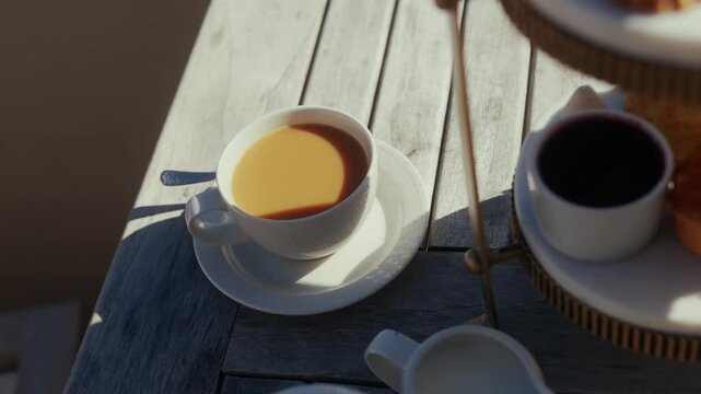 Warm morning light illuminates cups of coffee on a wooden table