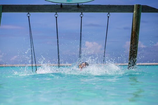 Water splash on a turquoise water tropical beach with a wooden slide in Maldives