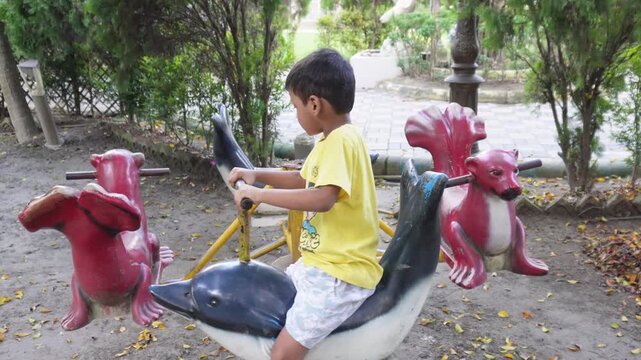 Young child riding animal themed merry go round at outdoor playground