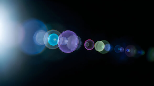 Anamorphic lens flare with colorful bokeh circles on black background, cinematic light leak effect for professional video overlay and photo editing. Vibrant optical flare featuring purple blue