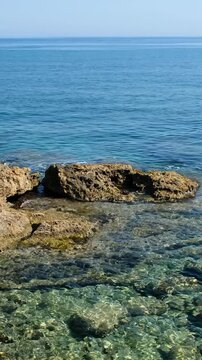 Vertical video of the rocky shore of Crete Island with blue clear Mediterranean sea water. Greece