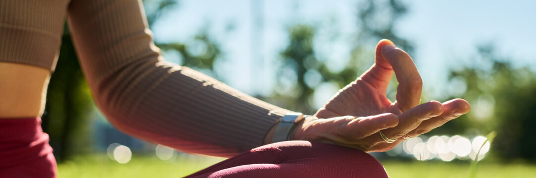 Caucasian woman practicing yoga and meditation outdoors in lotus position with hand in chin mudra gesture. Image suitable for mental health, mindfulness, and wellness advertising campaigns