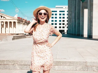 Young beautiful smiling hipster woman in trendy summer clothes. Sexy carefree woman posing on the street background at sunset. Positive model outdoors. Cheerful and happy in sunglasses and hat © halayalex