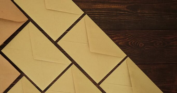Craft envelopes for letters pattern on a wooden brown table. Looped 4K stop motion animation