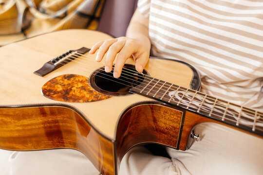 Woman play acoustic guitar in striped shirt closeup