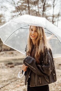 Smiling girl with transparent umbrella in rainy weather