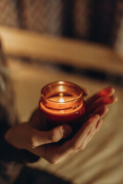 Girl hold scented candle in warm cozy home interior