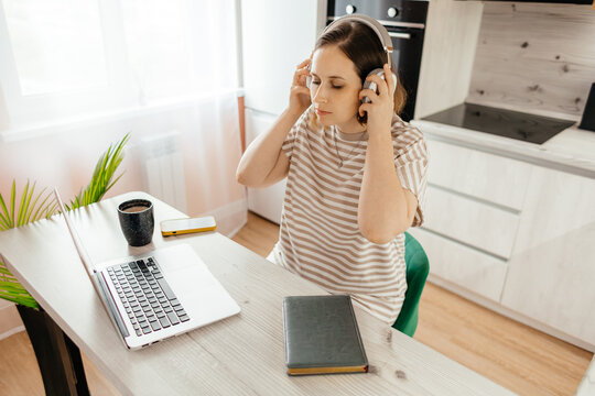 Woman with headphones at laptop during remote work