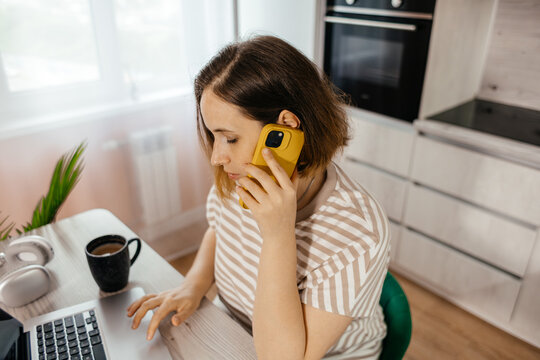 Woman work remotely on laptop and smartphone at home