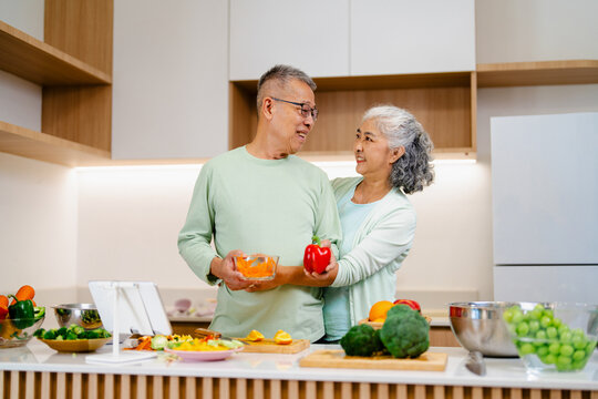 Asian mature couple preparing food together at home, retirement concept