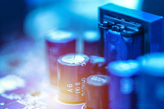 Close-up of electronic capacitors mounted on a circuit board with soft focus and glowing light effects. Electronics engineering and hardware technology concept.