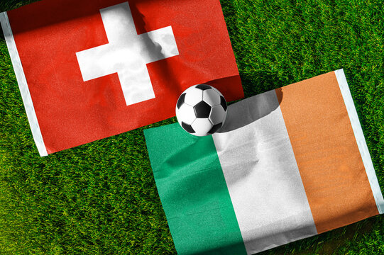 Switzerland vs. Republic of Ireland football match. National flags on green grass with soccer ball in the middle. Football background for international match.