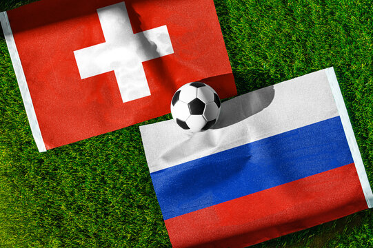 Switzerland vs. Russia football match. National flags on green grass with soccer ball in the middle. Football background for international match.