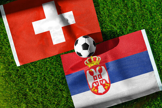 Switzerland vs. Serbia football match. National flags on green grass with soccer ball in the middle. Football background for international match.