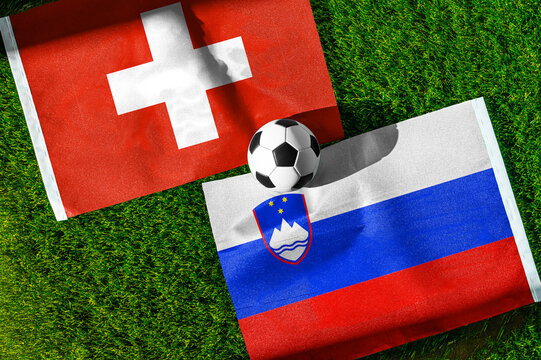 Switzerland vs. Slovenia football match. National flags on green grass with soccer ball in the middle. Football background for international match.