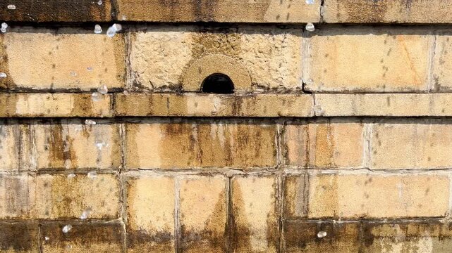 Centered circular outlet sits within an aged stained stone fountain wall
